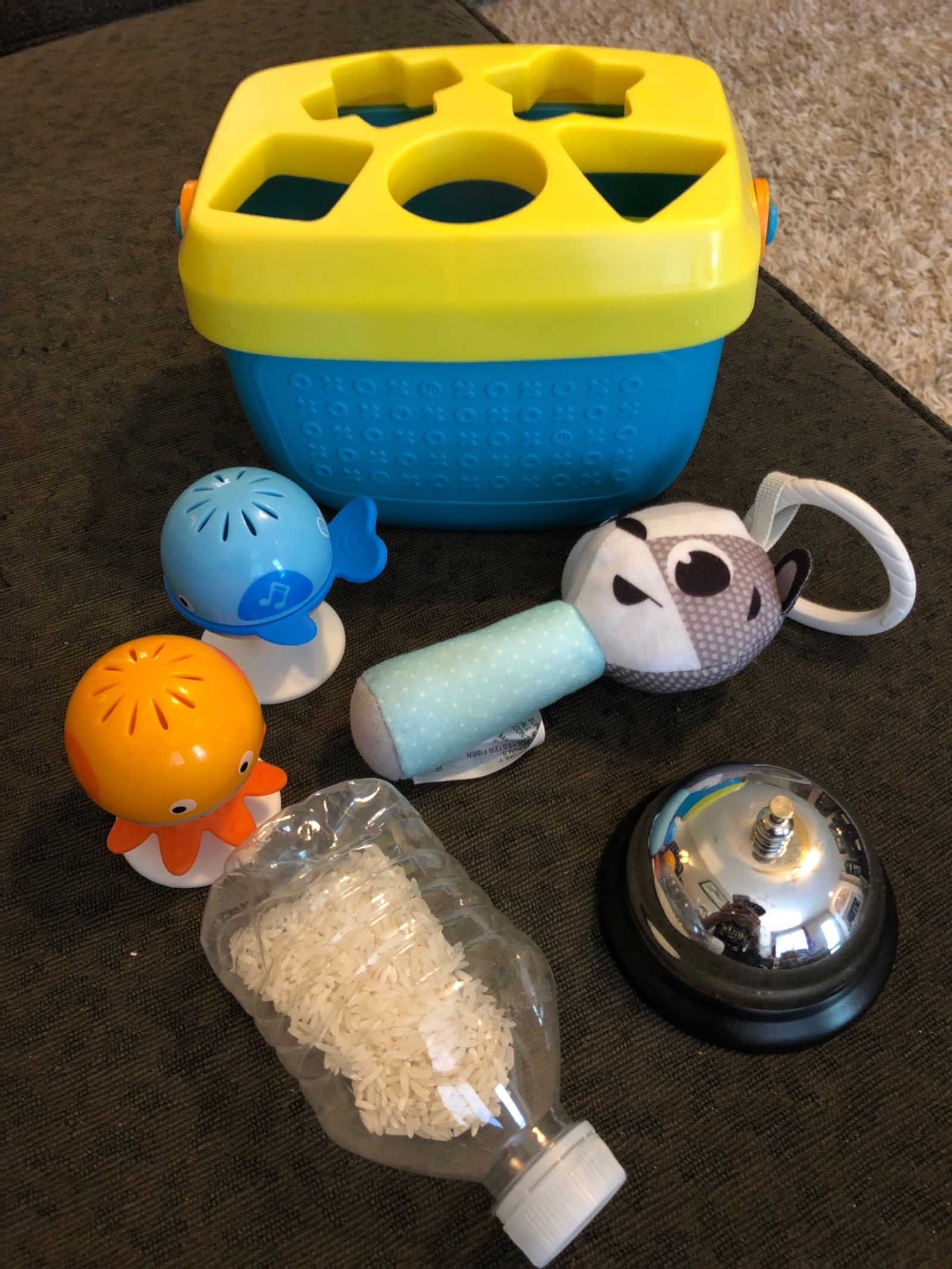 Photograph showing childrens toys that were sampled to create this pack: small sea animal shakers, soft rattler, silver bell, toy shapes bucket, and water bottle partially filled with rice.